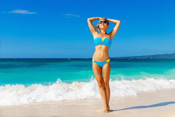 Mooie meisje in blauwe bikini plezier op een tropische bea — Stockfoto