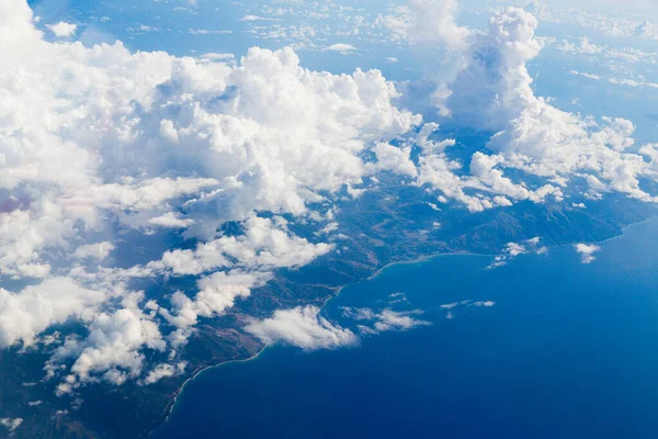 Air view from the plane window of the mountainous coastline of Taiwan among the clouds.