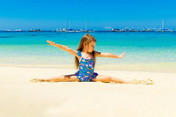 Gülümseyen Küçük Kız Kumlu Bir Tropik Plajda Jimnastik Yapıyor Seyahat — Stok fotoğraf