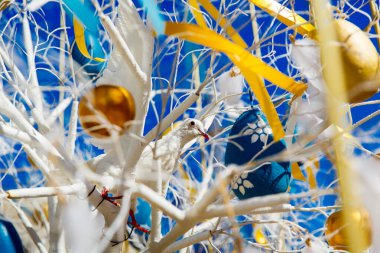 Renkli Paskalya yumurtaları mavi bahar gökyüzüne karşı bir ağaçta asılı duruyor. Bahar tatilleri için şehrin sokak dekorasyonunun kutlaması. Mutlu Paskalyalar.