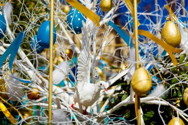 Renkli Paskalya yumurtaları mavi bahar gökyüzüne karşı bir ağaçta asılı duruyor. Bahar tatilleri için şehrin sokak dekorasyonunun kutlaması. Mutlu Paskalyalar.
