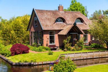 Giethoorn, Hollanda, 30 Mayıs 2021. Hollanda 'nın ünlü köyü Giethoorn geleneksel Hollanda evleri, bahçeleri, su kanalları ve ahşap köprüleri ile 