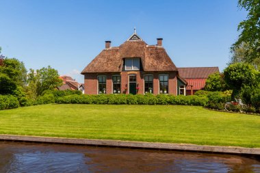 Giethoorn, Hollanda, 30 Mayıs 2021. Hollanda 'nın ünlü köyü Giethoorn geleneksel Hollanda evleri, bahçeleri, su kanalları ve ahşap köprüleri ile 