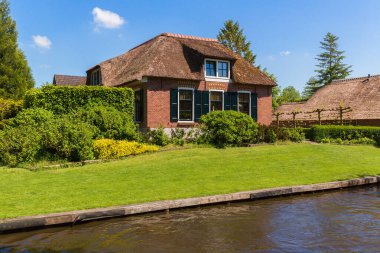 Giethoorn, Hollanda, 30 Mayıs 2021. Hollanda 'nın ünlü köyü Giethoorn geleneksel Hollanda evleri, bahçeleri, su kanalları ve ahşap köprüleri ile 