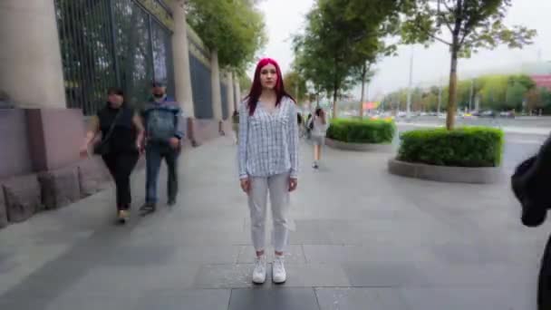 Tid förflutit tonåring flicka med rött hår står i centrum i upptagen gata tittar på kameran medan massor av människor går förbi. — Stockvideo