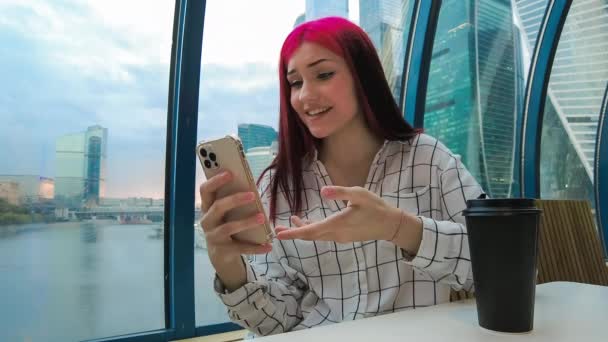 Mladá krásná ovlivňující blogger dívka v kavárně mluvení dělat videohovor pomocí smartphone se svými předplatiteli v sociálních sítích. — Stock video