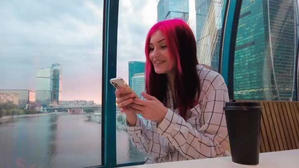 Unga vackra röda hår flicka i caféet är glada att få goda nyheter genom videosamtal med hjälp av smartphone från sina abonnenter i sociala nätverk. — Stockvideo