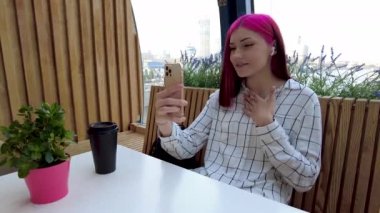 Güzel kızıl saçlı, etkili blog yazarı kafede konuşan kız sosyal ağlardaki aboneleriyle video görüşmesi yapıyor..