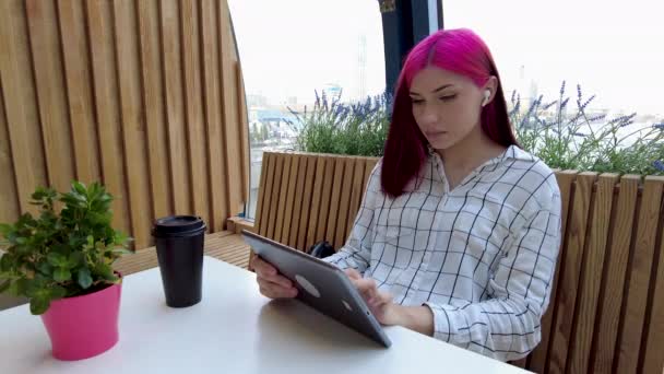 Krásná zrzavá studentka pracuje jako vzdálený zaměstnanec s tabletem v kavárně. — Stock video