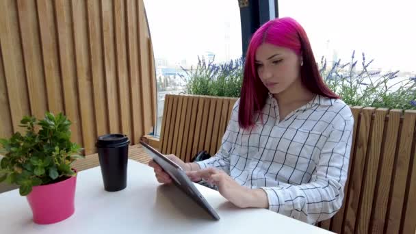 Belle étudiante rousse travaille comme employée à distance avec tablette dans un café. — Video