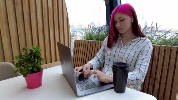 Linda menina estudante ruiva bebendo café e funciona como funcionário remoto com laptop no café. — Vídeo de Stock
