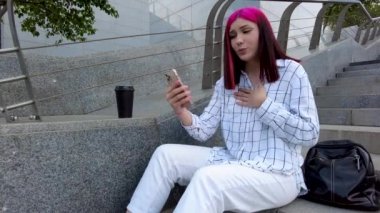 Güzel, kızıl saçlı genç kız karaoke 'de akıllı telefonuyla rap yapıyor sokakta merdivenlerde oturuyor..