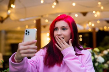 Şaşırmış kızıl saçlı etkili blogcu kız sosyal ağlardaki aboneleriyle video görüşmesi yapıyor..