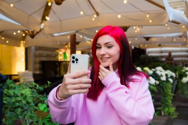 Güzel kızıl saçlı, etkili blog yazarı kafede konuşan kız sosyal ağlardaki aboneleriyle video görüşmesi yapıyor..