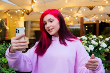 Güzel kızıl saçlı, etkili blog yazarı kafede konuşan kız sosyal ağlardaki aboneleriyle video görüşmesi yapıyor..