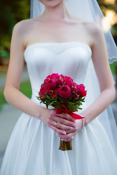Panna młoda trzyma Bukiet ślubny z czerwonych róż. — Zdjęcie stockowe