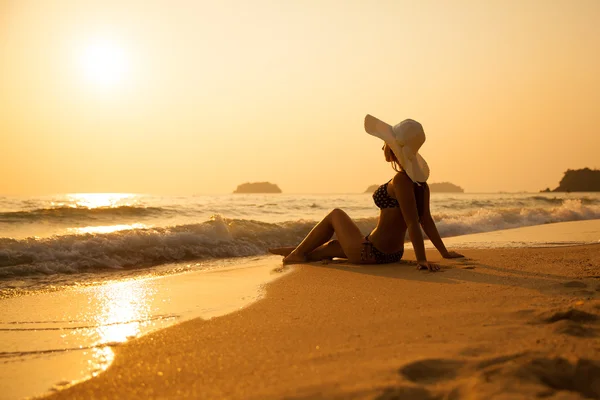 Jovencita con sombrero de paja en una playa tropical al atardecer. Verano —  Fotos de Stock