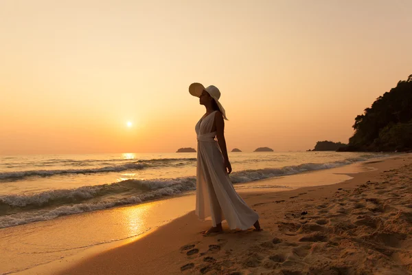 Menina bonita nova em um vestido branco e chapéu de palha em uma trópica — Fotografia de Stock