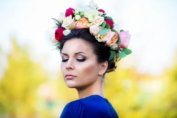 Portrait of a beautiful young woman in a wreath of roses, outdoo — Stock Photo, Image