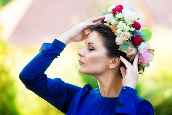 Portrait of a beautiful young woman in a wreath of roses, outdoo — Stock Photo, Image