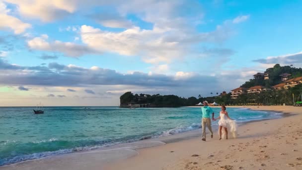 Gelukkige bruid en bruidegom plezier op een tropisch strand. — Stockvideo