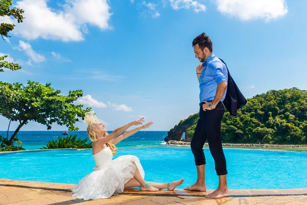 Feliz novia y novio junto a la piscina infinito. Mar tropical en el bac — Foto de Stock