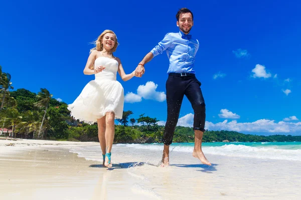 Happy bride and groom having fun on a tropical beach — Stock Photo, Image