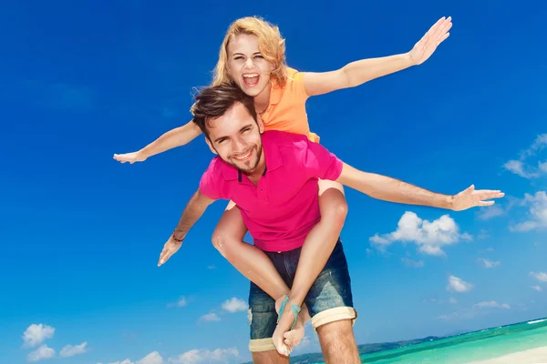 Young beautiful couple having fun on a tropical beach. — Stock Photo, Image