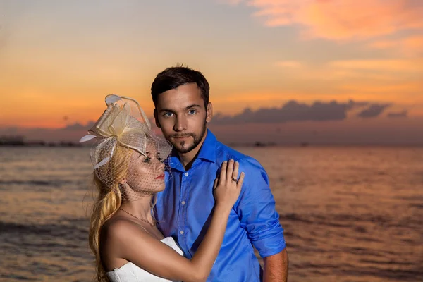Sposo e sposo su una spiaggia tropicale con il tramonto nella schiena — Foto Stock