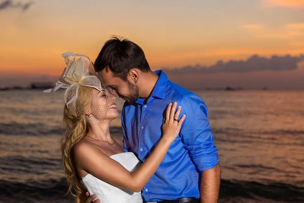 Novia y novio en una playa tropical con la puesta de sol en la parte posterior —  Fotos de Stock