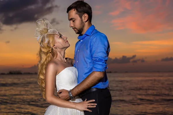 Novia y novio en una playa tropical con la puesta de sol en la parte posterior — Foto de Stock