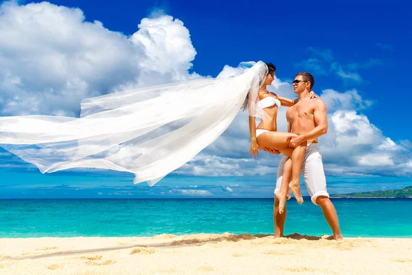Happy bride and groom having fun on a tropical beach — Stock Photo, Image
