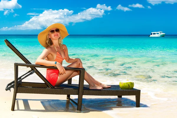 Beautiful young girl in bikini is sitting on a sun lounger coast — Stock Photo, Image