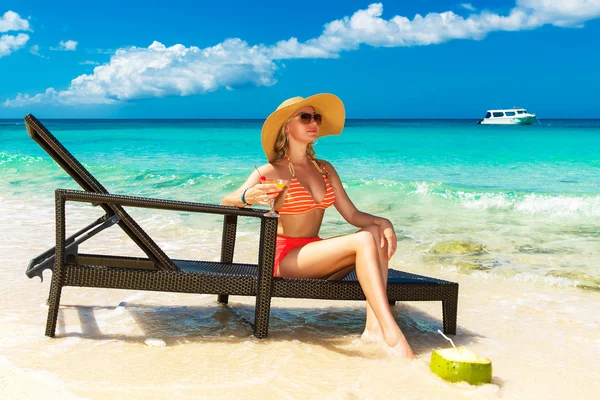 Beautiful young girl in bikini is sitting on a sun lounger coast — Stock Photo, Image