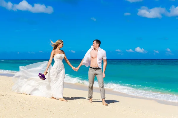 Happy bride and groom having fun on a tropical beach — Stock Photo, Image