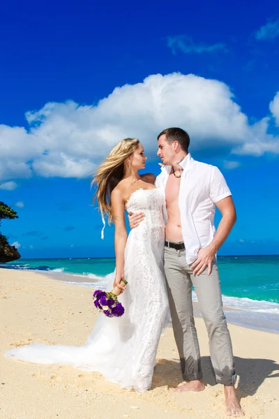 Gelukkige bruid en bruidegom plezier op een tropisch strand — Stockfoto