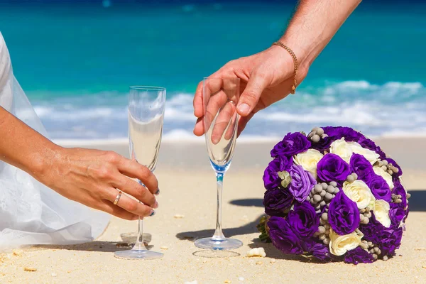 Wedding bouquet and two glasses of champagne on the sand. Male a — Stock Photo, Image