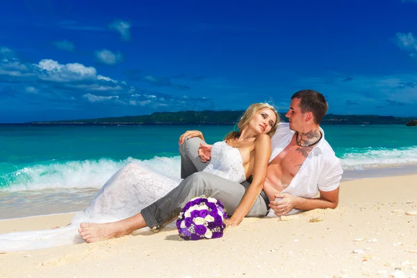 Brautpaar an einem tropischen Strand. Brautstrauß im Vordergrund — Stockfoto