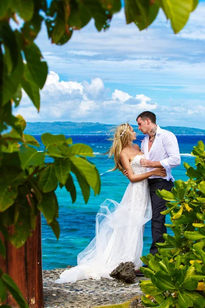 Happy bride and groom having fun on a tropical beach under the p — Stock Photo, Image