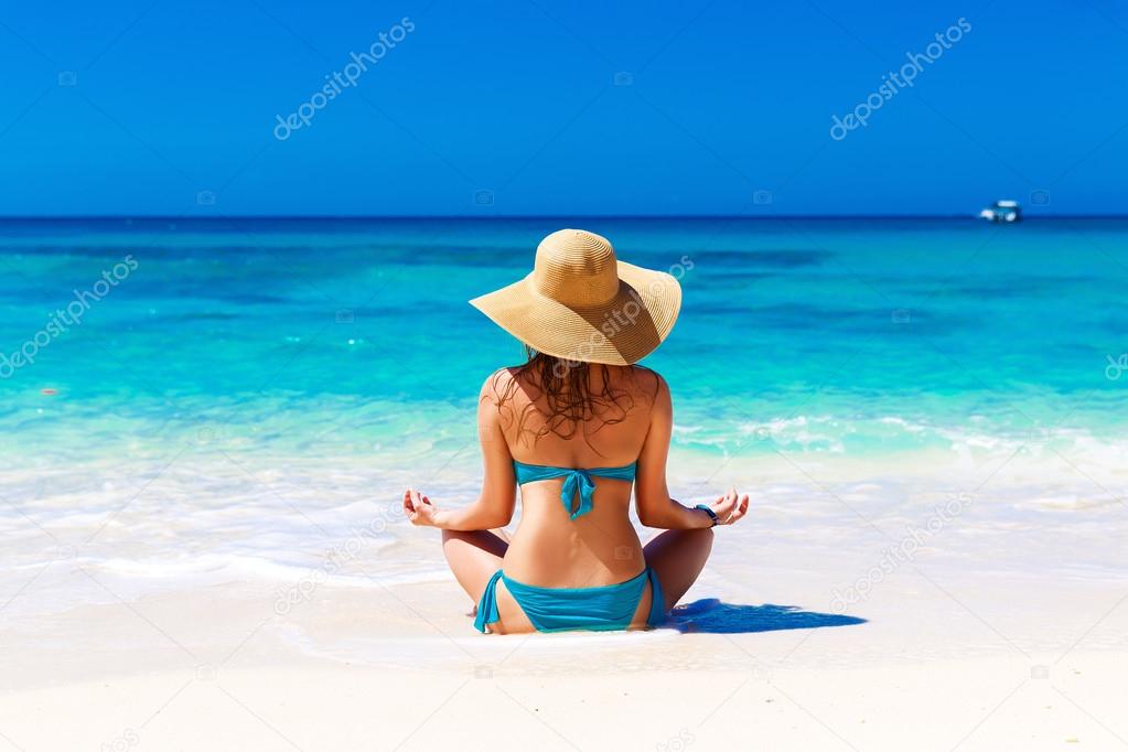  Young girl in a straw hat on a tropical beach. Summer vacation 