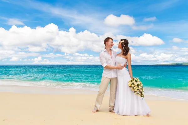 Happy bride and groom having fun on a tropical beach — Stock Photo, Image