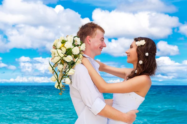 Happy bride and groom having fun on a tropical beach — Stock Photo, Image