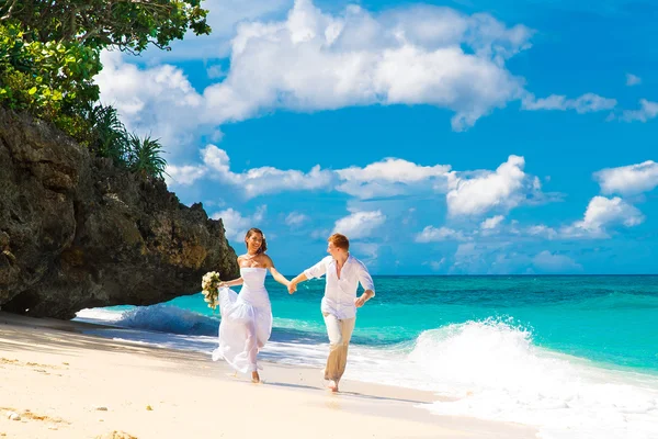 Happy bride and groom having fun on a tropical beach — Stock Photo, Image