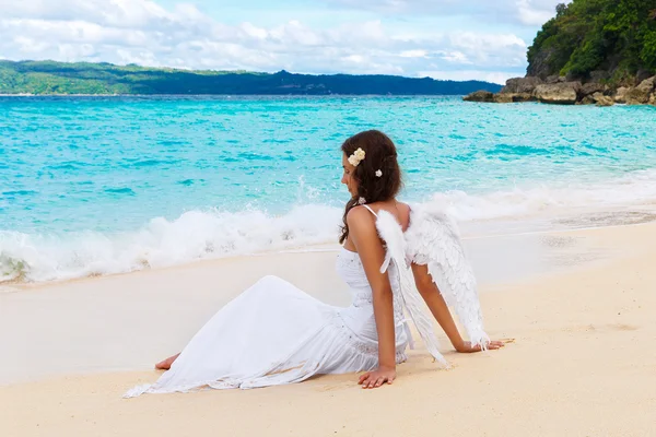 Mooie jonge bruid met engel vleugels aan de zeekust. Tropica — Stockfoto