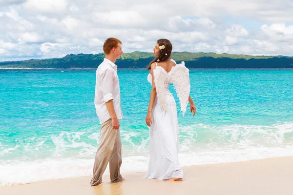 The groom and a beautiful young bride with angel wings on the se — Stock Photo, Image