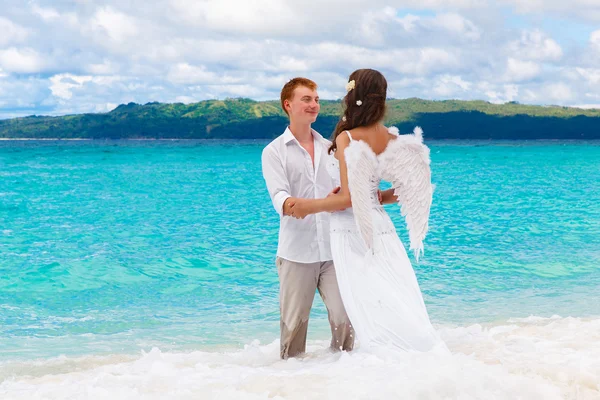 The groom and a beautiful young bride with angel wings on the se — Stock Photo, Image