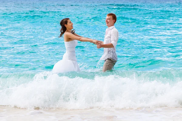 Happy bride and groom having fun on a tropical beach — Stock Photo, Image