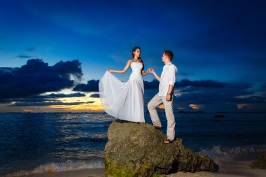 Gelin ve damat backg günbatımında ile tropikal bir plajda