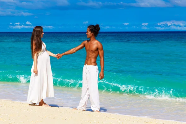 Gelukkig en jonge zwangere paar plezier op een tropisch strand. — Stockfoto