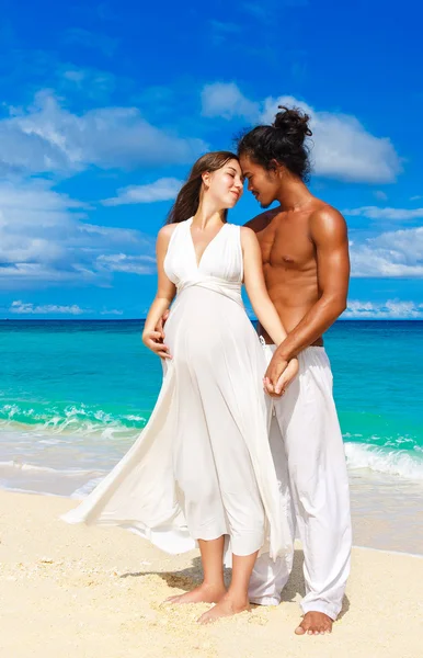 Šťastný a mladá těhotná pár baví na tropické pláži. — Stock fotografie